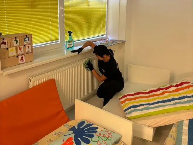 Pracovníčka BODYTEP utiera parapet a radiátor pod oknom so žalúziou