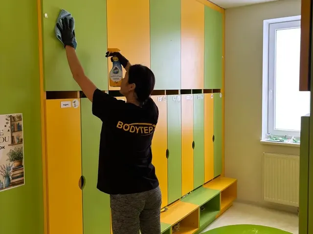 Pracovníčka BODYTEP umýva hornú časť farebných šatňových skriniek