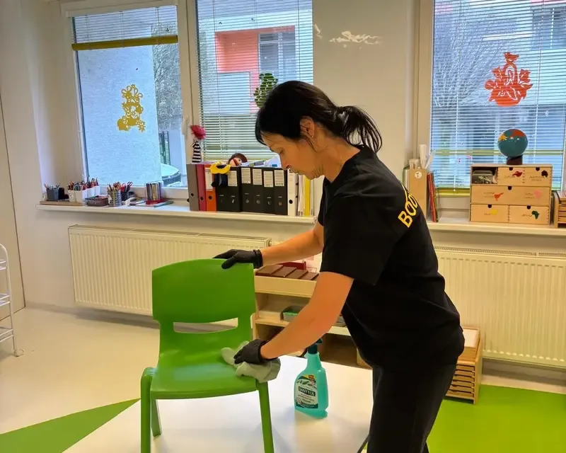 Pracovníčka BODYTEP vo firemnom tričku utiera nábytok pri upratovaní priestoru